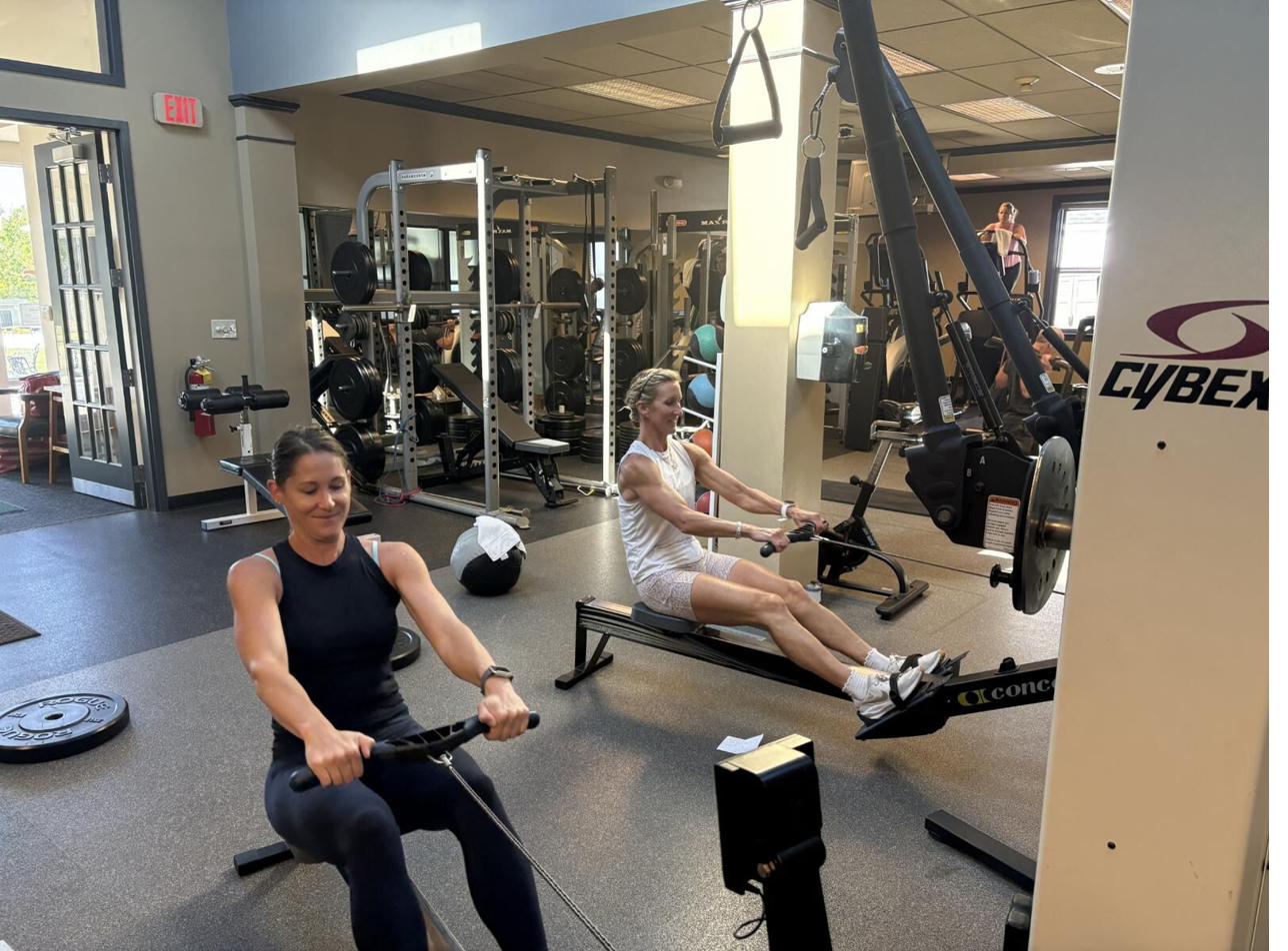 Two athletes training side by side on rowing machines