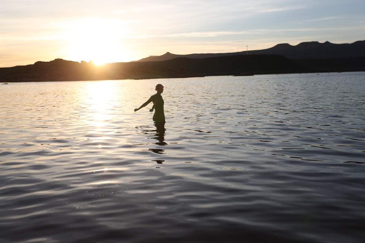 Silhouette standing in still water at sunset